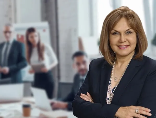 A woman in a suit standing with her arms crossed.